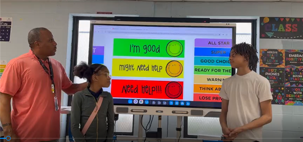  Teacher and two students standing in front of whiteboard